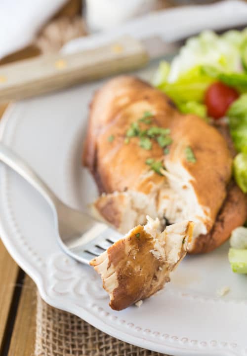 A fork with a piece of tender chicken breast that has been poached in tea and honey.