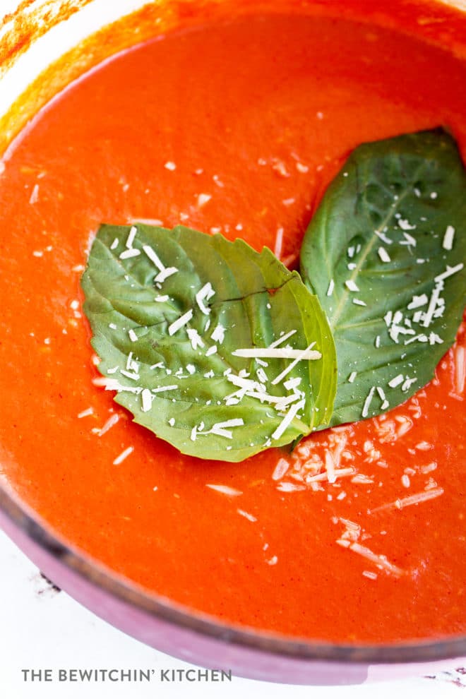 Close up of a parmesan tomato vodka sauce garnished with parmesan cheese and basil leaves.