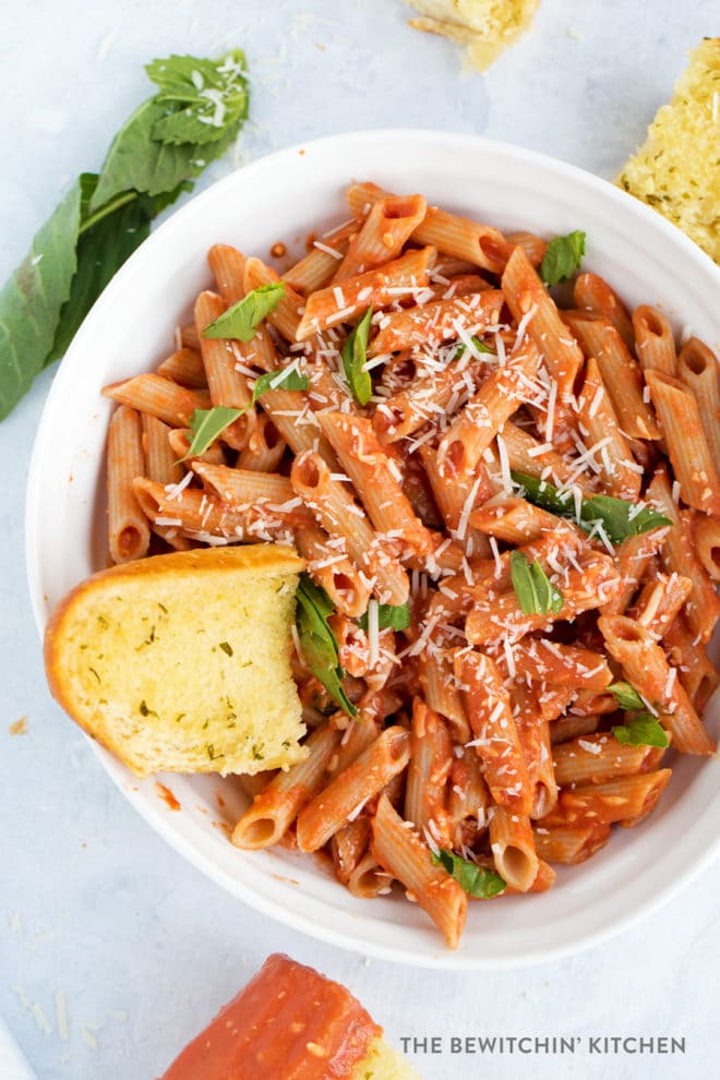Penne with vodka sauce in a beautiful bowl with basil garnish.