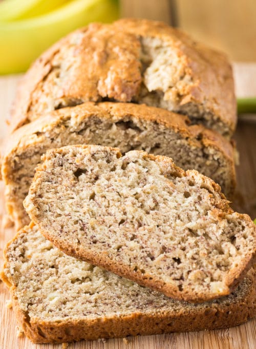 Sliced banana bread stacked on a cutting board.