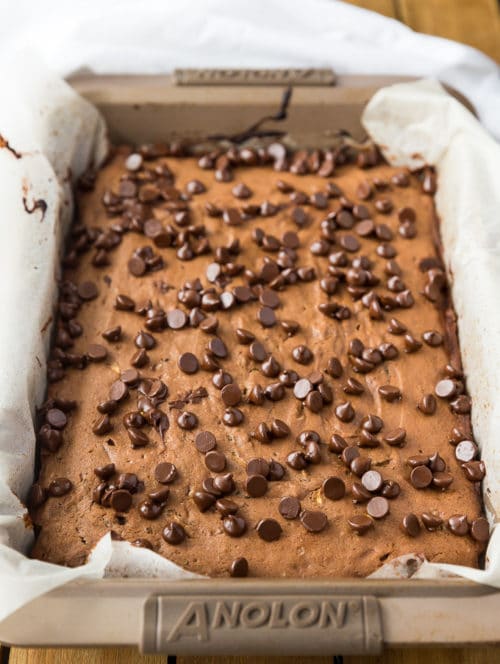 Chocolate Zucchini Cake in a baking pan lined with parchment paper, fresh out of the oven.