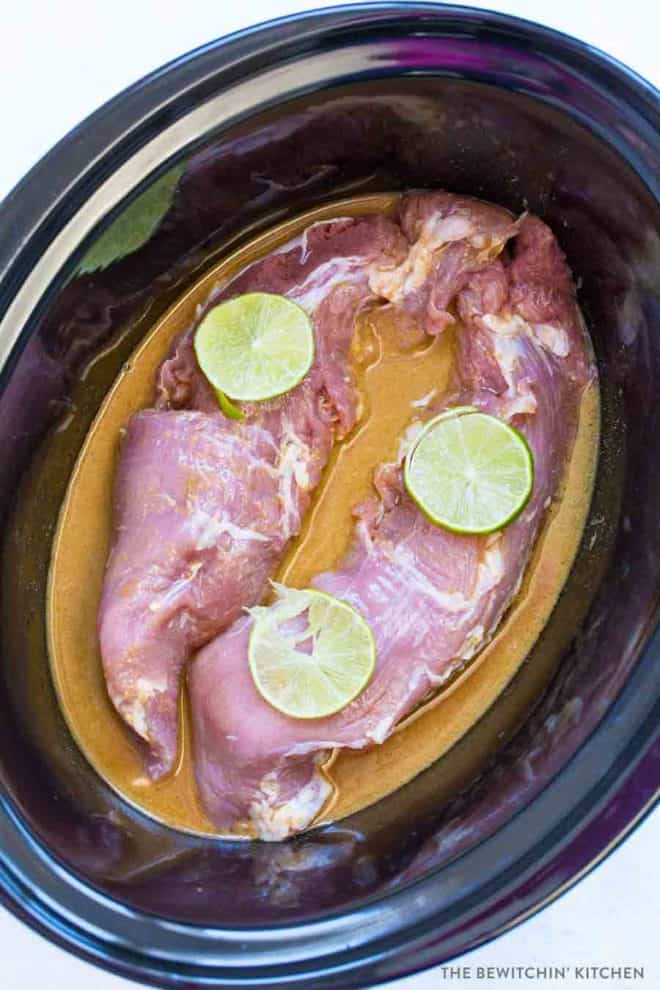 Two pork tenderloins laying in a sesame ginger lime sauce in a Crockpot.