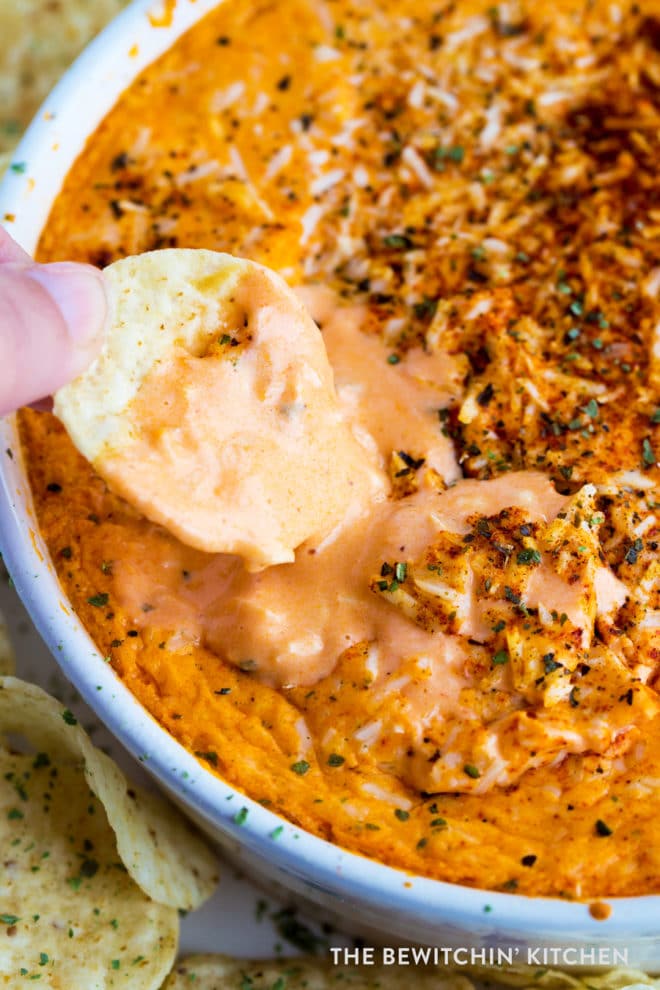 A chip dipping into a gooey, cheesy hot buffalo chicken dip.