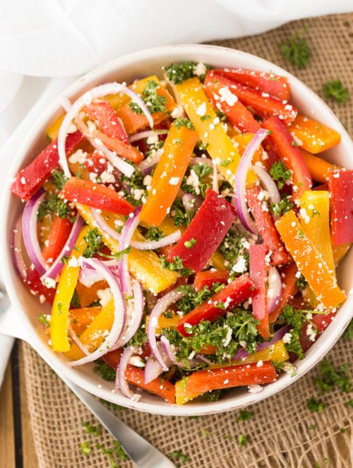 An overhead look at a marinated bell pepper salad with red onions and feta cheese.