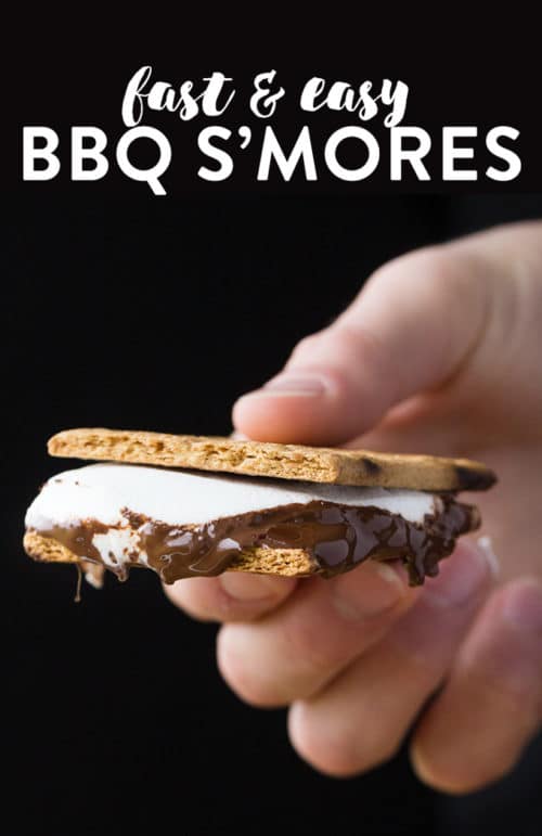 A hand holding a grilled smore against a black background