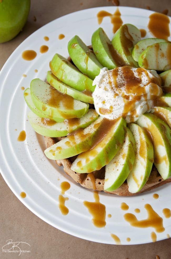 Overhead shot of sliced apples over a waffle with a caramel sauce drizzle.
