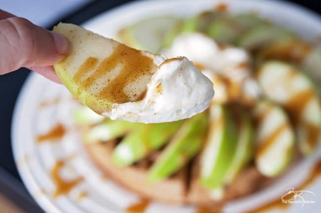 A slice of apple dipped in no sugar caramel sauce, whipped cream, and dusted in cinnamon.