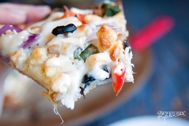 Greek Pizza - pizza crust topped with tangy greek vinaigrette, chicken, red pepper, spinach, olives , purple onion, feta and mozzarella. Finished with a greek tzatziki drizzle. So much yum happening right here. | thebewitchinkitchen.com