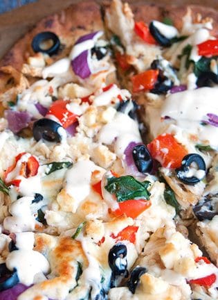 Greek Pizza - pizza crust topped with tangy greek vinaigrette, chicken, red pepper, spinach, olives , purple onion, feta and mozzarella. Finished with a greek tzatziki drizzle. So much yum happening right here. | thebewitchinkitchen.com