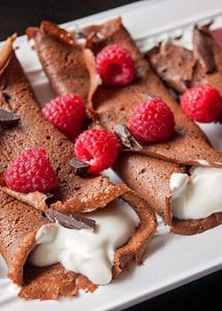 This recipe for healthy chocolate crepes is gluten free and grain free. It's filled with a protein packed greek yogurt and whipped cream mixture and topped with raspberries and dark chocolate. Add this to your healthy breakfast recipes and healthy dessert recipe board!