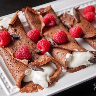 This recipe for healthy chocolate crepes is gluten free and grain free. It's filled with a protein packed greek yogurt and whipped cream mixture and topped with raspberries and dark chocolate. Add this to your healthy breakfast recipes and healthy dessert recipe board!