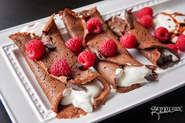 This recipe for healthy chocolate crepes is gluten free and grain free. It's filled with a protein packed greek yogurt and whipped cream mixture and topped with raspberries and dark chocolate. Add this to your healthy breakfast recipes and healthy dessert recipe board!