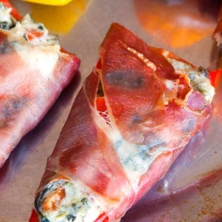 Spinach artichoke stuffed peppers wrapped in prosciutto. Add this to your appetizer recipes. Spinach dip, bell peppers, prosciutto - it sounds like heaven. It has a little kick from jalapenos too. The perfect party food recipe. | thebewitchinkitchen.com