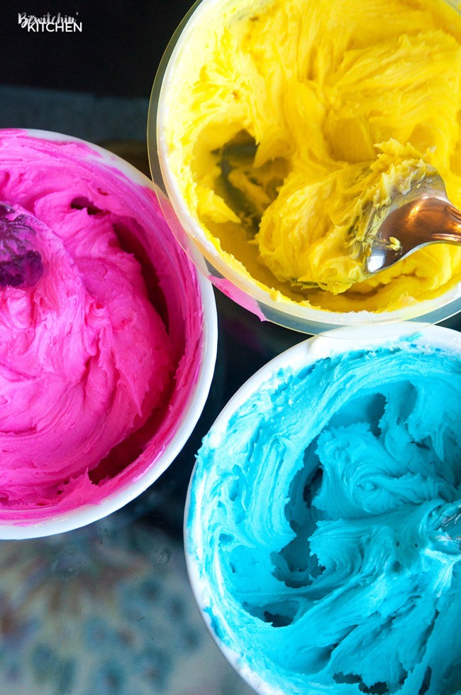 containers of pink, yellow, and blue frosting