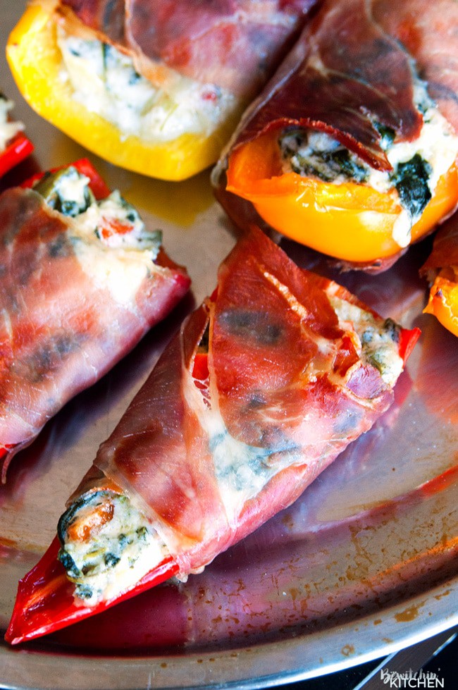 Spinach artichoke stuffed peppers wrapped in prosciutto. Add this to your appetizer recipes. Spinach dip, bell peppers, prosciutto - it sounds like heaven. It has a little kick from jalapenos too. The perfect party food recipe. | thebewitchinkitchen.com