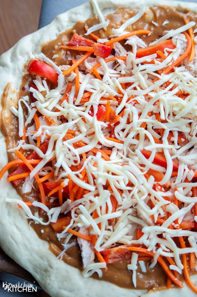 adding ingredients to thai pizza crust