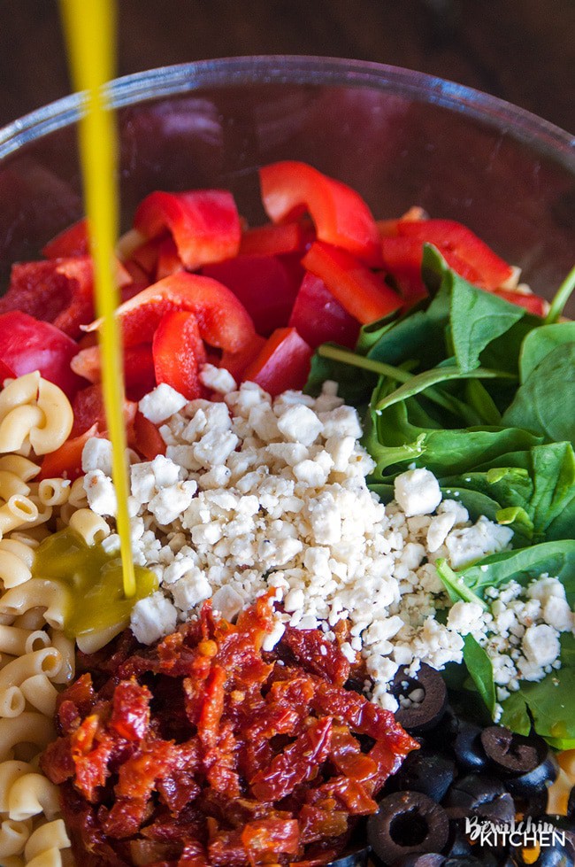 Pesto Pasta Salad - this tangy twist on a macaroni salad is my new favorite summer salad recipe. Sundried tomatoes, smart veggie pasta, spinach, feta cheese, red pepper, and olives tossed in a homemade honey pesto vinaigrette. Also makes a delicious and nutritious addition to a school lunch.