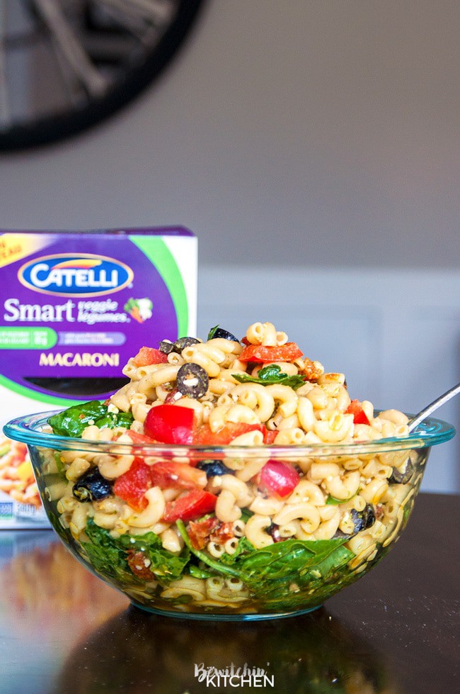 Pesto Pasta Salad - this tangy twist on a macaroni salad is my new favorite summer salad recipe. Sundried tomatoes, smart veggie pasta, spinach, feta cheese, red pepper, and olives tossed in a homemade honey pesto vinaigrette. Also makes a delicious and nutritious addition to a school lunch.