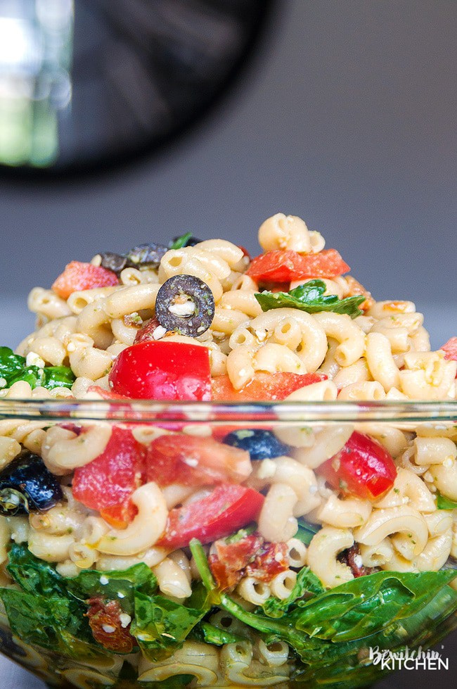 Close up of pesto pasta salad topped with a pesto vinaigrette.