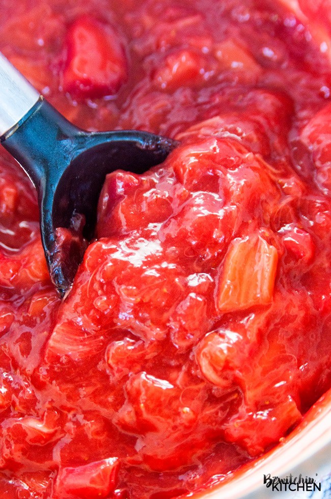 closeup of a large spoon stirring strawberry rhubarb filling