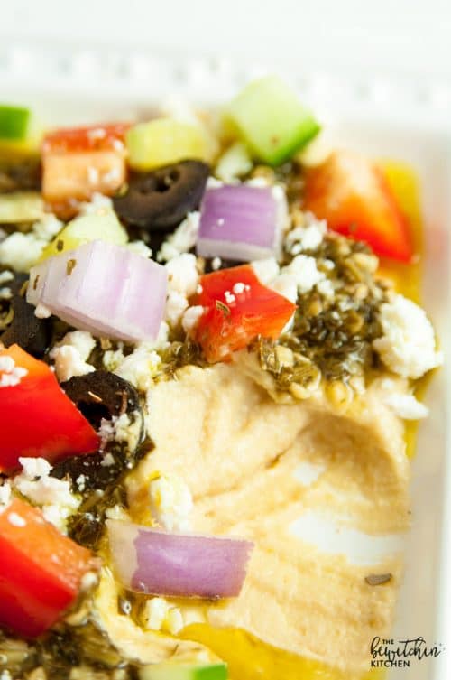 Layered Pesto Greek Dip - EASIEST DIP RECIPE EVER! This Mediterranean inspired appetizer uses hummus, pesto, feta, peppers, olives, and cucumbers. Goes great with veggies and chips. 21 Day Fix approved and a healthy appetizer recipe.