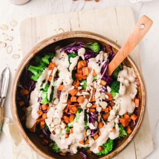 This paleo winter bowl recipe has roasted sweet potato, broccoli, finely shredded red cabbage, pulled together with a creamy vegan almond and honey dressing. Serve as a side dish or add some chicken or tofu for a healthy lunch or dinner.