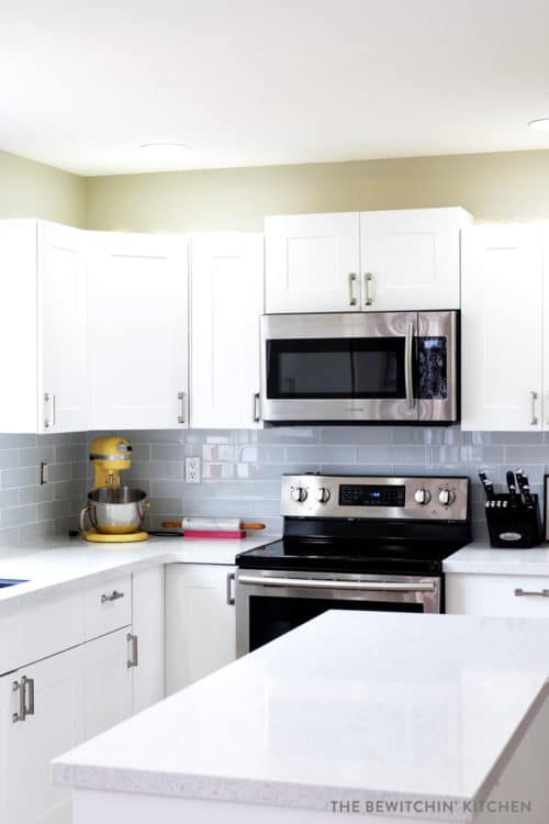 This all white kitchen was the result of a DIY kitchen renovation. Using Home Depot's Eurostyle Kitchen Cabinets in Oxford and Silestone's Stellar Snow. The backsplash is Sassi's glass subway tile in nordic ice. More before and after photos in the post.