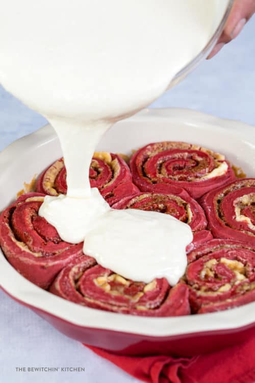 Delicious cream cheese glaze poured over red velvet cinnamon rolls. 