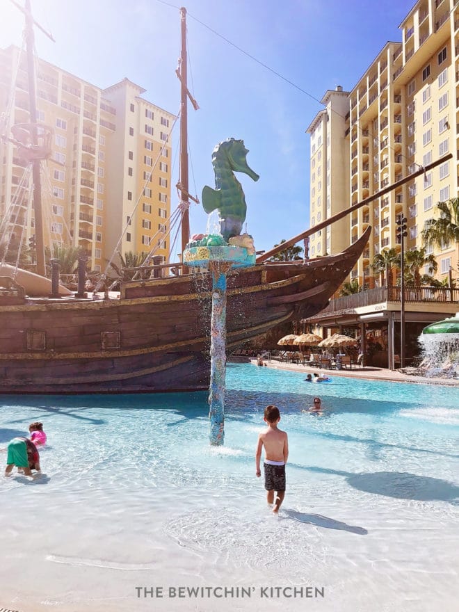 Child in the shallow end of the pool with a pirate ship behind him at Lake Buena Vista Resort in Orlando.