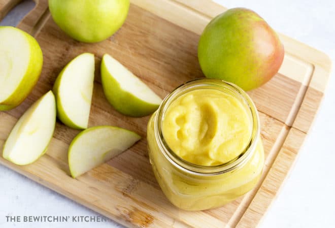 Homemade applesauce on a cutting board with granny smith apples