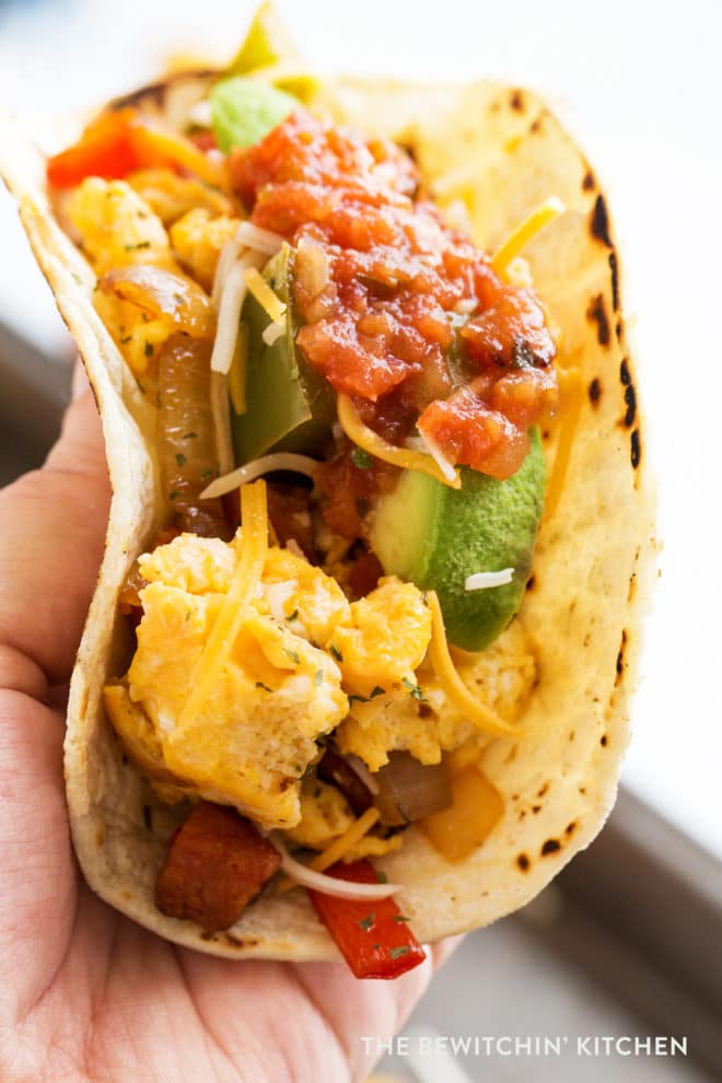 Breakfast tacos with cheese, salsa, avocado, chorizo and peppers.