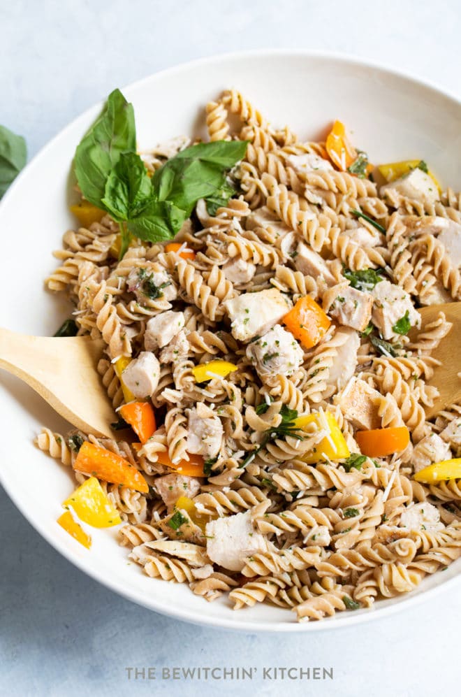 Chicken pasta salad with bell peppers, parmesan cheese, and basil in a bowl.