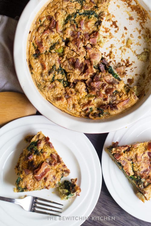 over head shot of a spinach and bacon quiche with a piece missing in the pie.