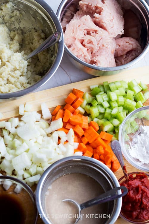 bowls of ground chicken, mashed cauliflower, and other ingredients with a variety of chopped vegetables