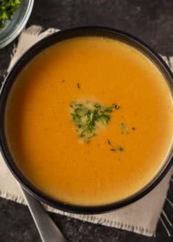 overhead of low carb pumpkin soup topped with fresh herbs