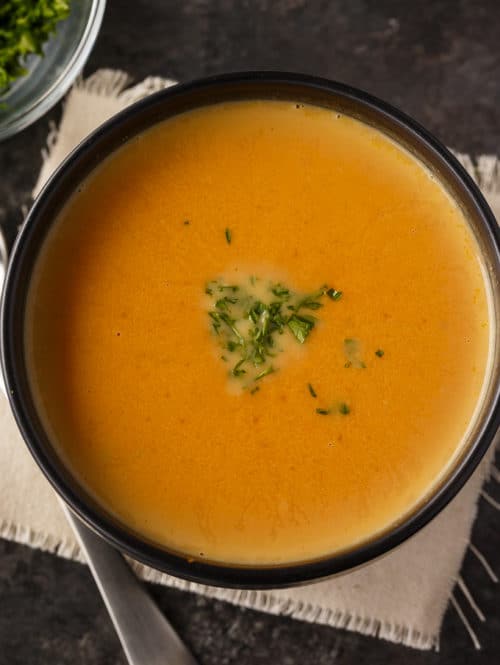 overhead of low carb pumpkin soup topped with fresh herbs