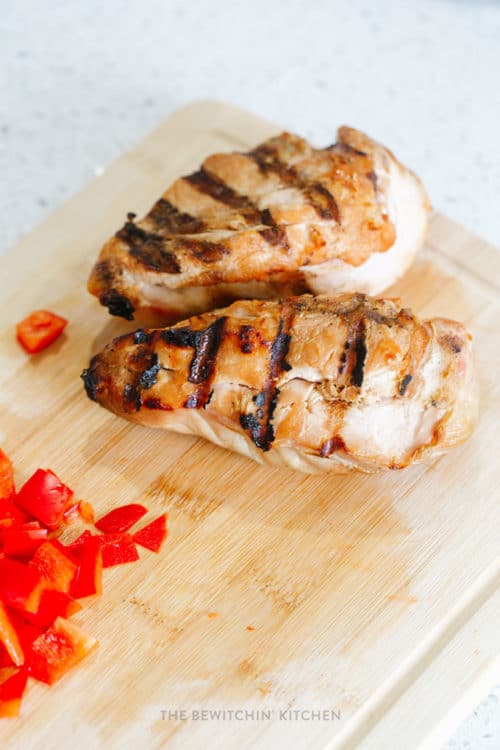 grilled chicken on a cutting board with red pepper