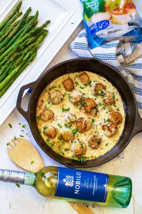 bottle of Nobilo wine with asparagus and pan of creamy scallops