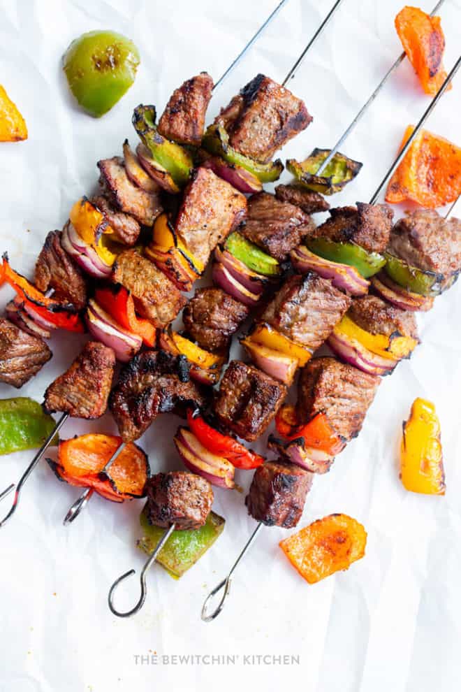 fajita steak skewers on a while background with roasted peppers