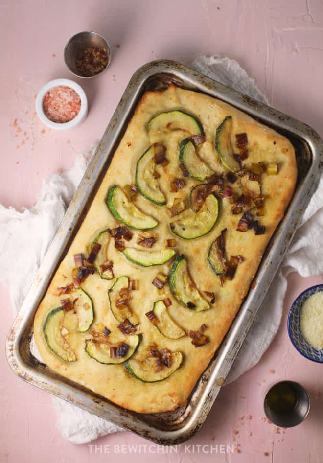 overhead of homemade focaccia bread with caramelized leeks and sliced zucchini