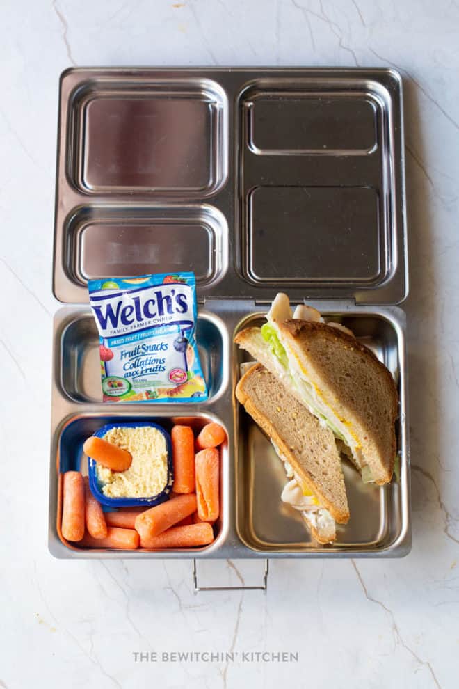 Easy school lunch idea 1 - Welch's Fruit Snacks, turkey sandwich on gluten free bread, baby carrots dipped in hummus in a Planetbox Bento box for kids school lunch.