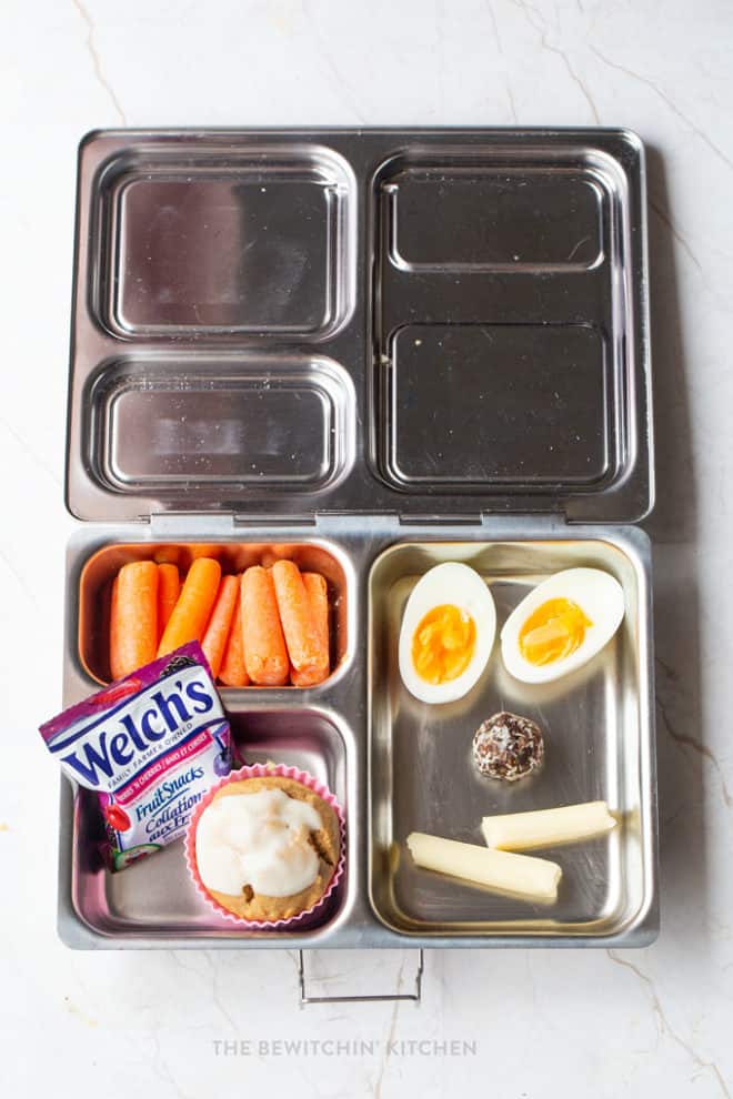 Perfect kids lunch idea - A bento box with baby carrots, Welch's Fruit Snacks, healthy muffin, hard boiled egg, snack bite, and cheese string. 