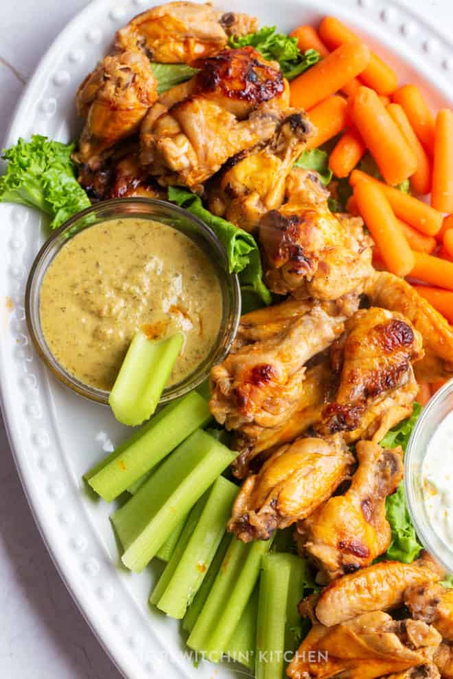 a platter of healthy honey hot wings with vegetables and a vegan ranch sauce