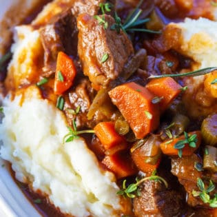 slow cooker red wine beef stew served over garlic whipped potatoes