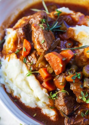 slow cooker red wine beef stew served over garlic whipped potatoes