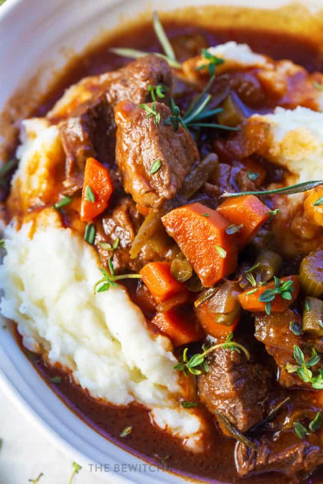 slow cooker red wine beef stew served over garlic whipped potatoes