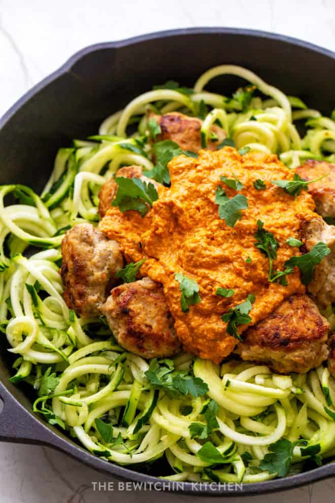 romesco chicken meatballs over a bed of zucchini noodles in a cast iron skillet