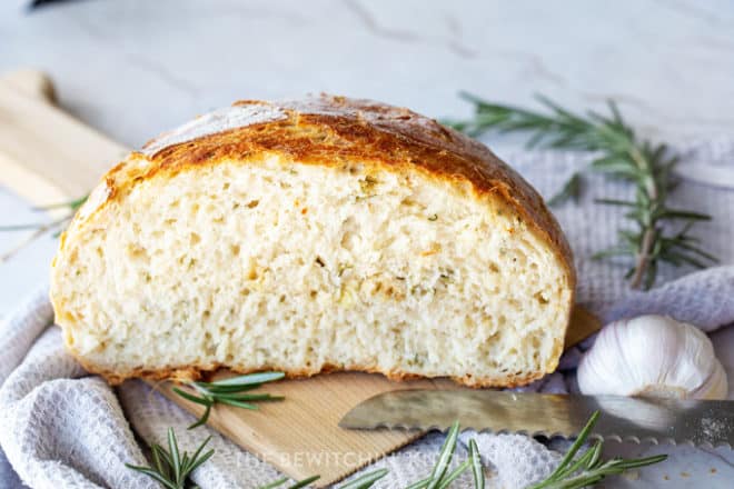 Sliced rosemary garlic homemade bread with pieces of rosemary and garlic showing throughout the loaf.