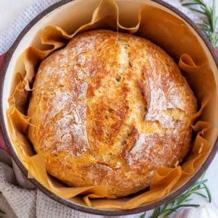 rosemary garlic bread in a dutch oven lined with parchment paper