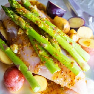 asparagus with chicken, honey mustard, chicken and potatoes on top of foil